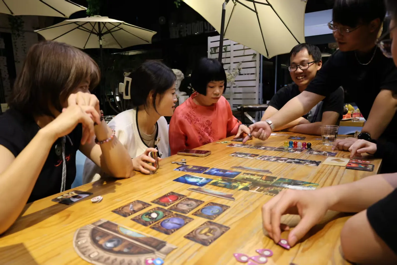 Players leaning over a Mysterium board on a cafe terrace in Kunming